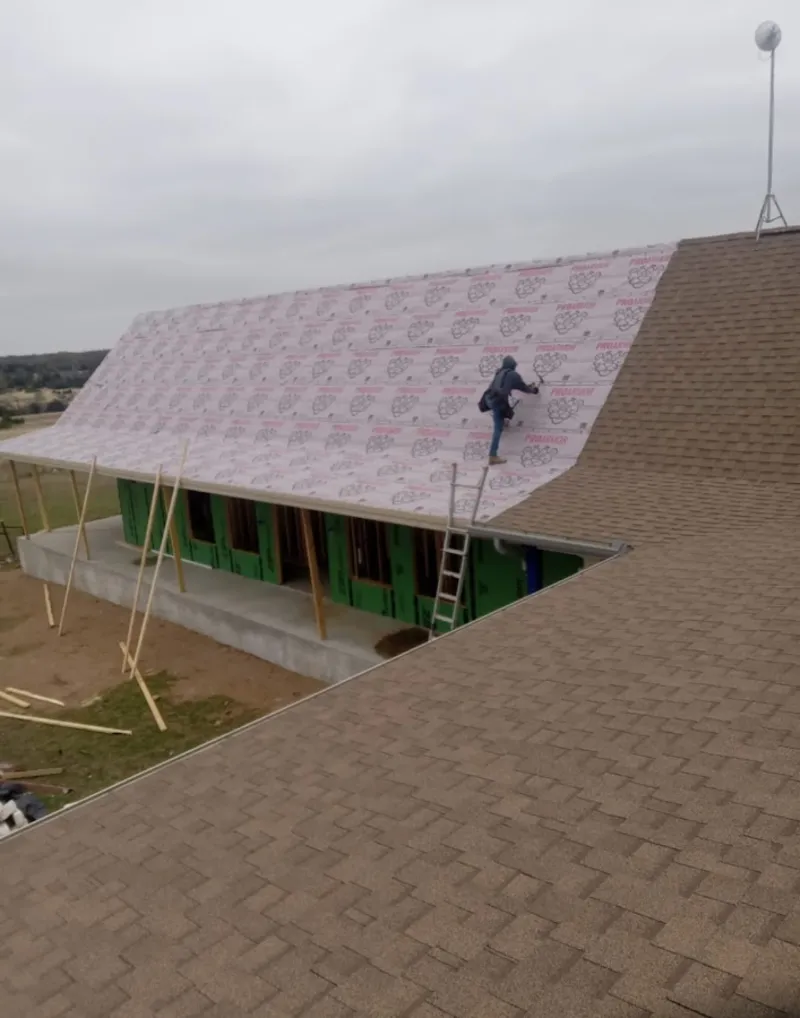 Worker preparing underlayment for a metal roof installation in Watertown